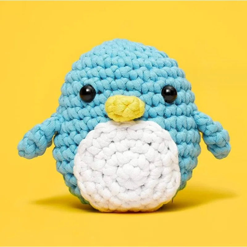 Blue and white crocheted penguin with yellow beak, shown as the project made from the materials kit