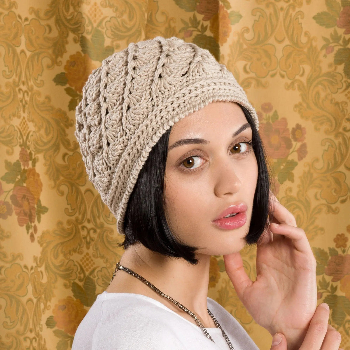 Model wearing a cream crochet cloche hat with an openwork pattern