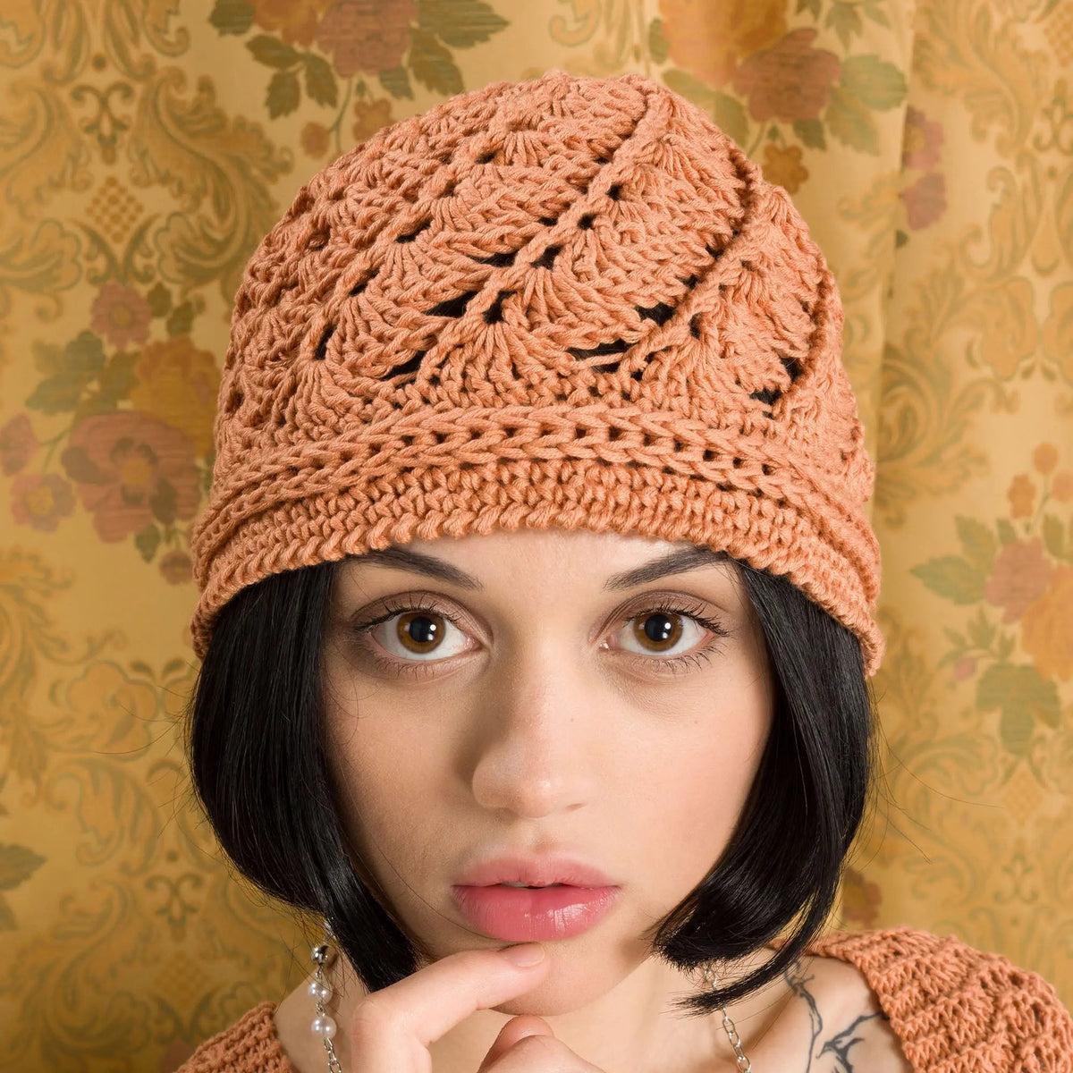 Model wearing a rust-colored crochet cloche hat