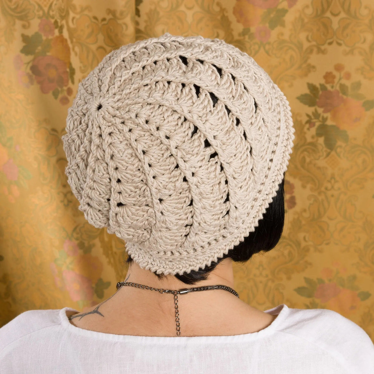 Back view of a cream crochet cloche worn on a model