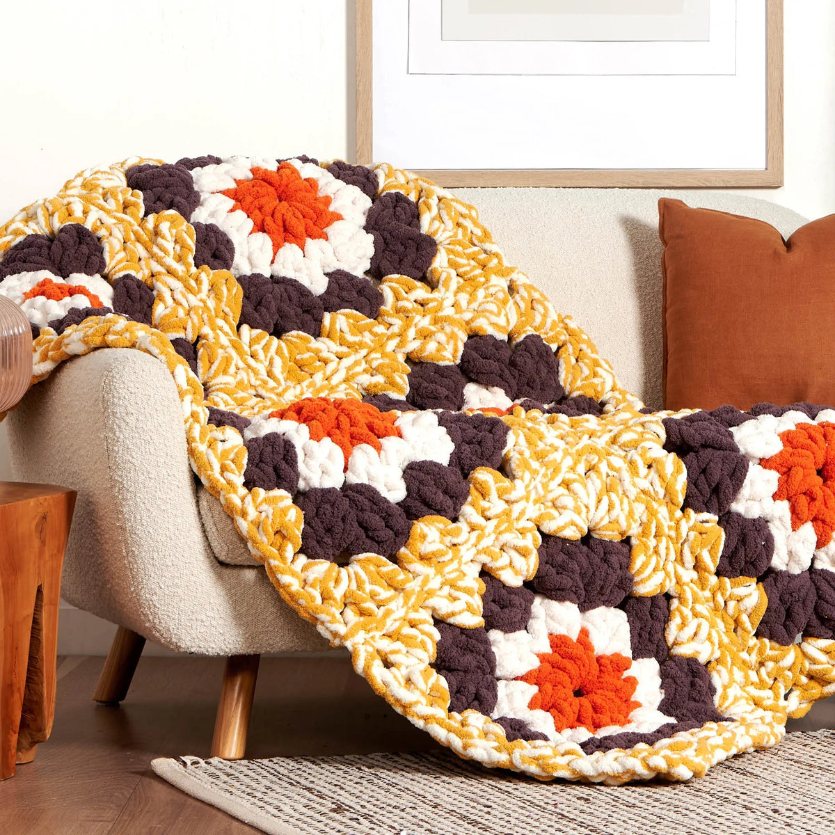 Chunky granny square blanket draped over upholstered seating