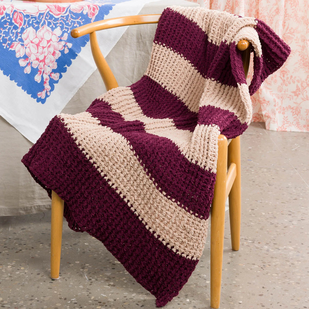 Burgundy and cream ribbed crochet blanket draped over a chair