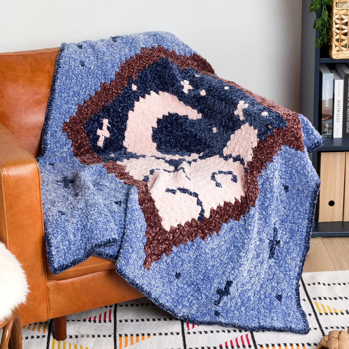 Blue moon-and-stars crochet blanket draped over brown seating