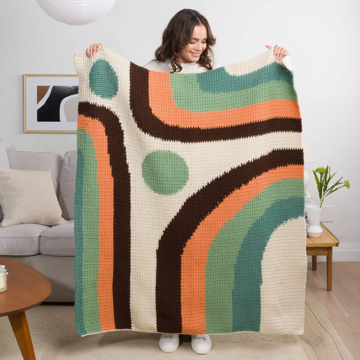 Model holding the Calm Current blanket with flowing retro color blocks