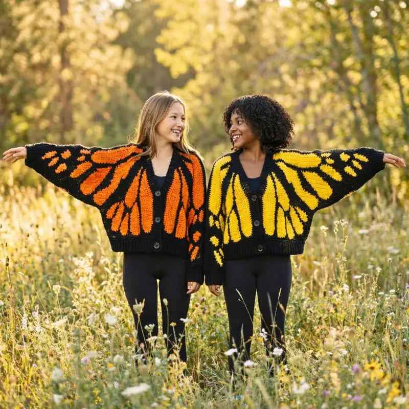Two models wearing orange and yellow butterfly-wing crochet cardigans outdoors