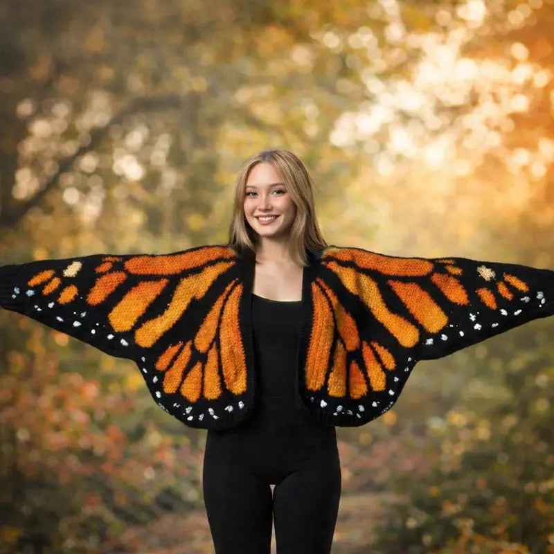 Model holding out the orange and black wings of a crochet butterfly cardigan