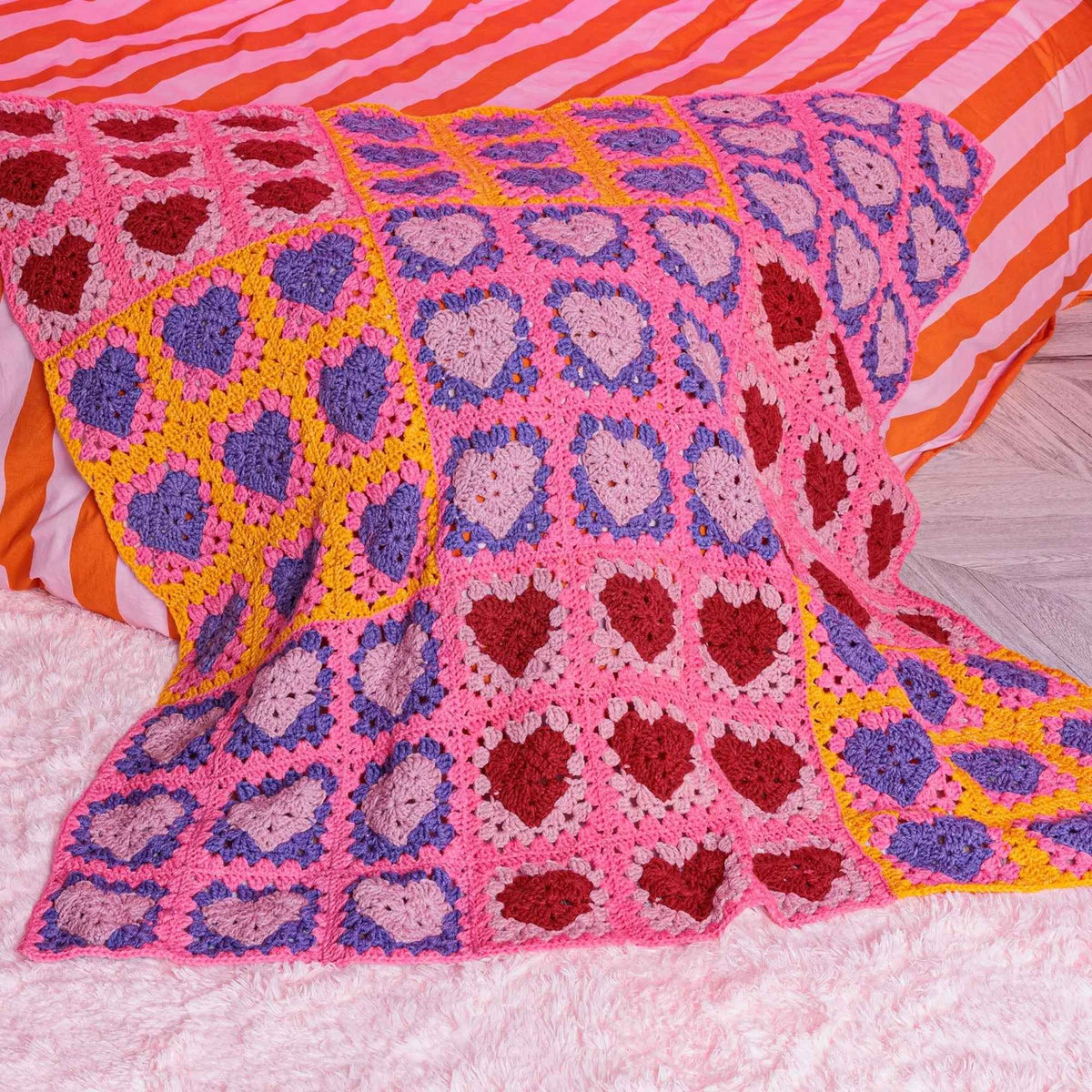 Heart-motif crochet blanket draped across a bed