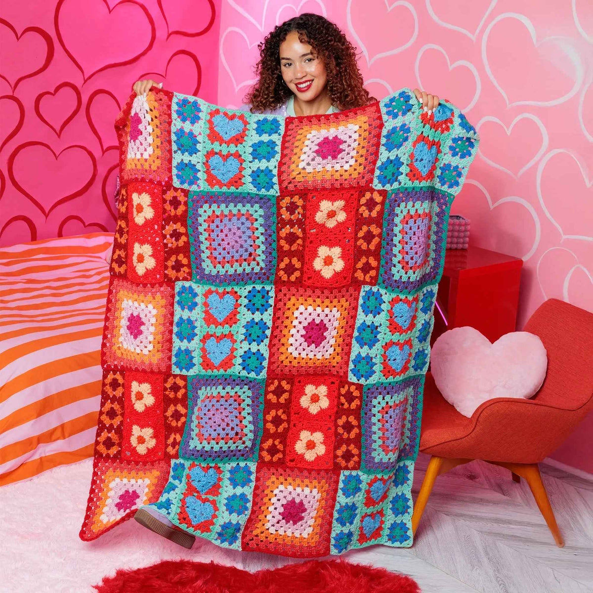 Model holding a colorful motif crochet blanket