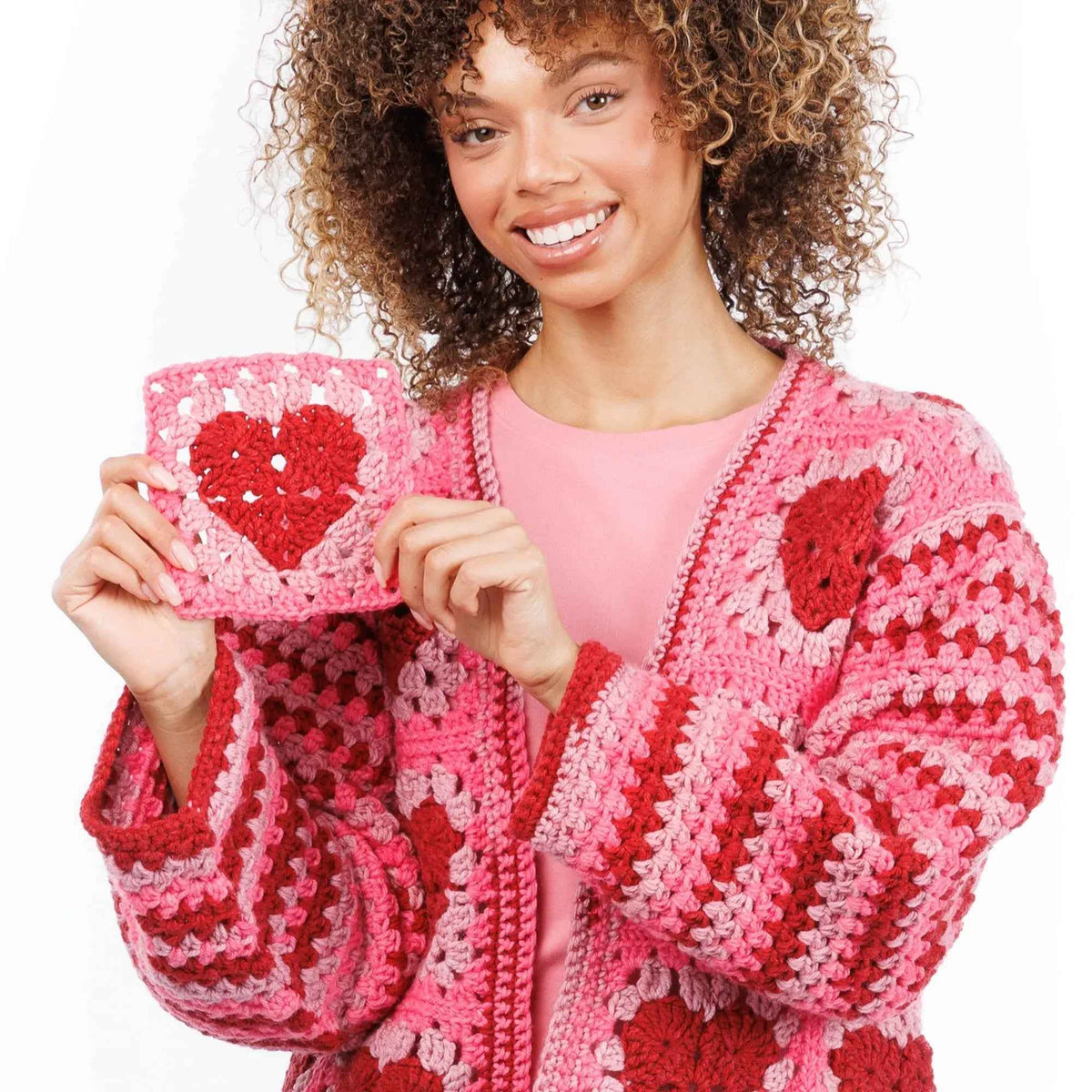 Model holding a heart crochet square beside the cardigan