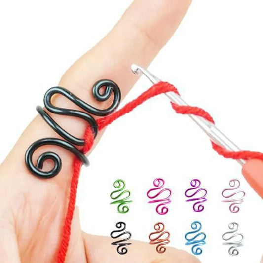Black wire crochet tension ring worn on a finger to guide red yarn; other colors shown for illustration