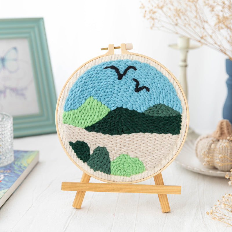 Green hills and black birds beneath a blue sky in a hoop