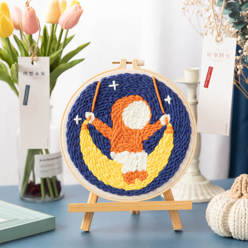 Orange astronaut sitting on a yellow crescent in a starry hoop design
