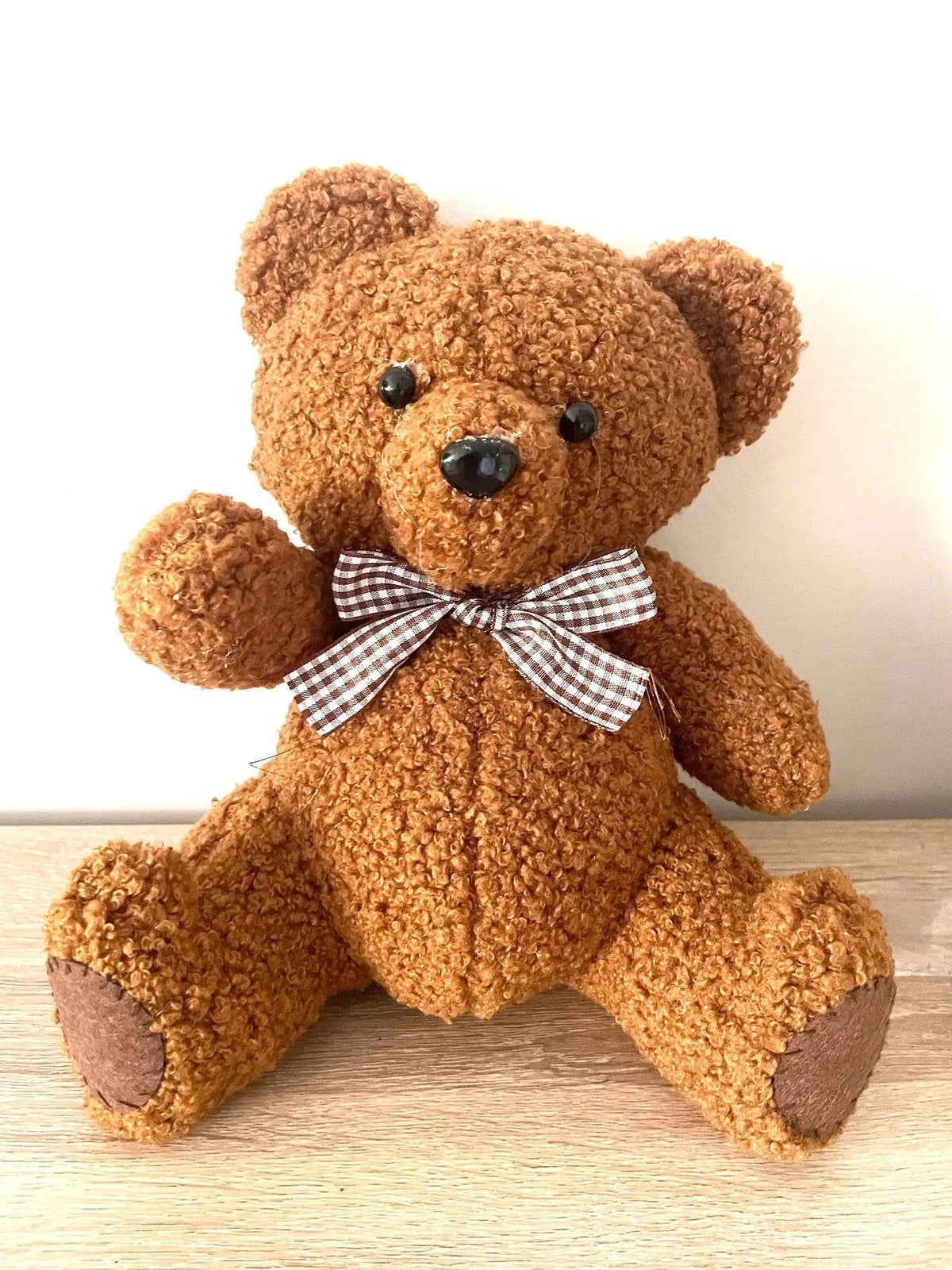 Brown fabric teddy bear with a gingham neck bow