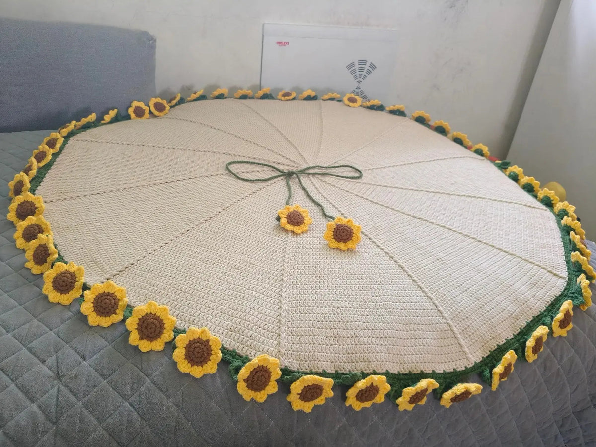 Round sunflower-edged crochet blanket spread on a bed