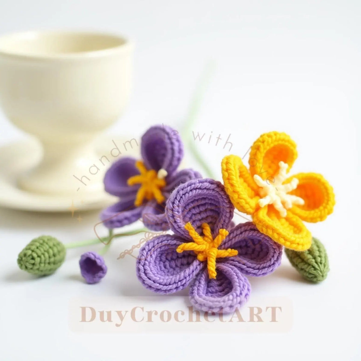 Purple and yellow crochet flowers beside a cup