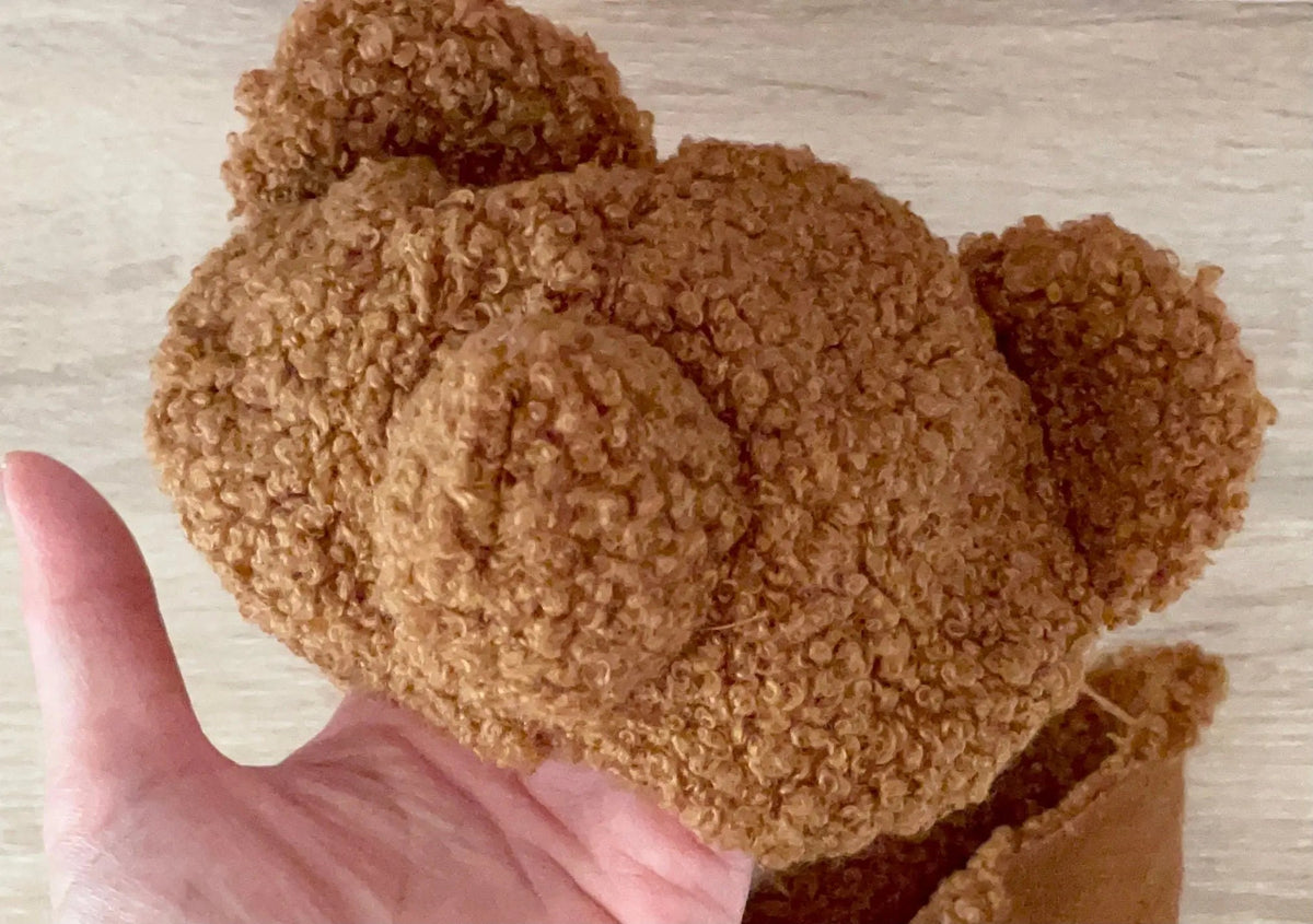 Hand holding a sewn teddy bear head